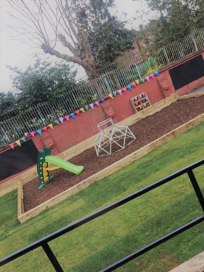 The outdoor play area with a slide, climbing frame and bark chippings