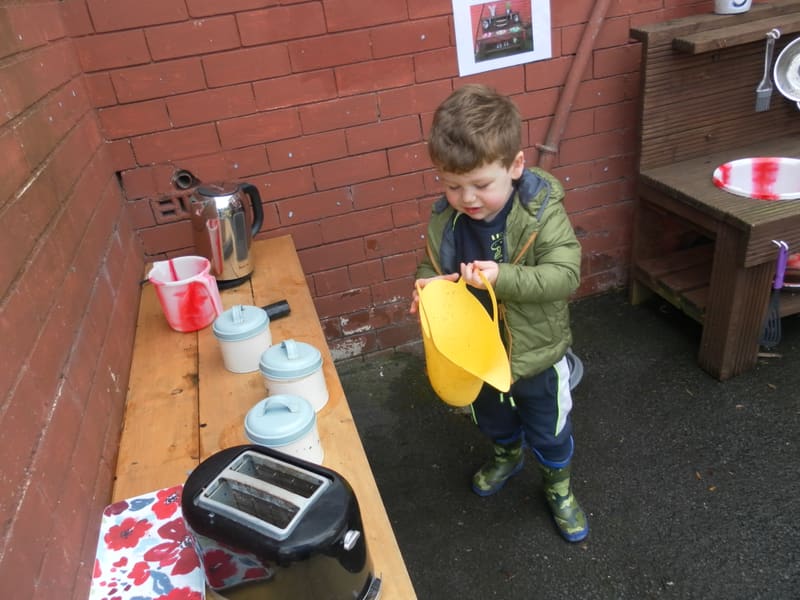 A child playing at the outdoor kitchen bench in the garden